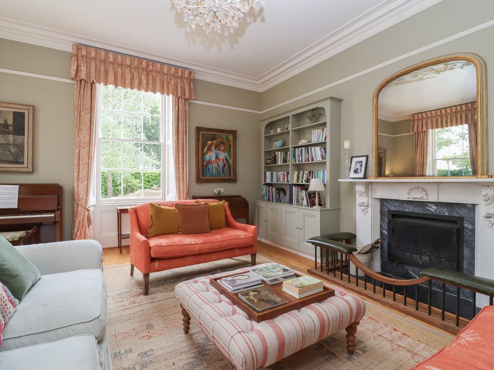 A living room with a piano and bookshelf at The Old Vicarage in Merriott