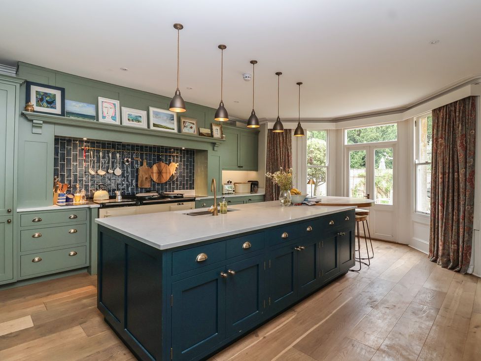 A kitchen with a central island and stools at The Old Vicarage in Merriott