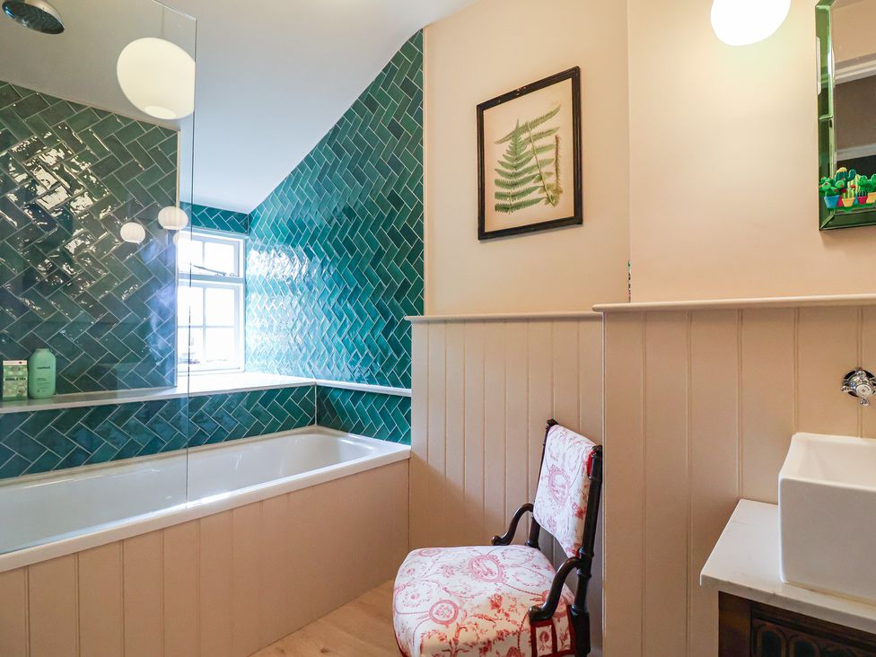 A bathroom with a bathtub, sink, and a chair at The Old Vicarage in Merriott
