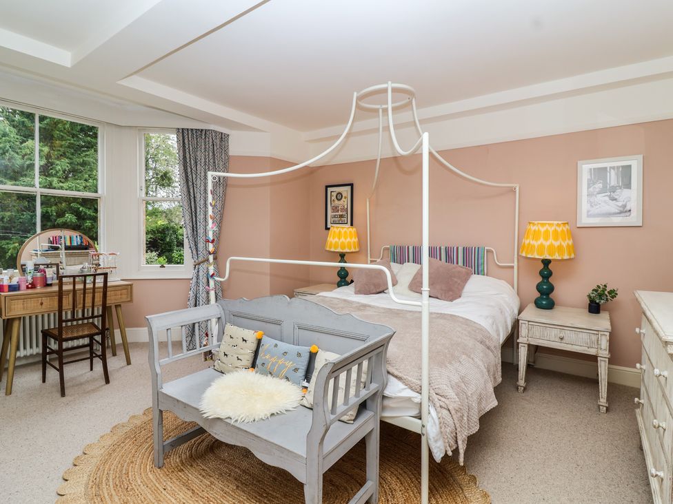A bedroom with a bed, bench, and dressing table at The Old Vicarage in Merriott