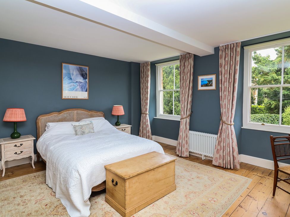 A bedroom with a bed, nightstand and curtains at The Old Vicarage in Merriott