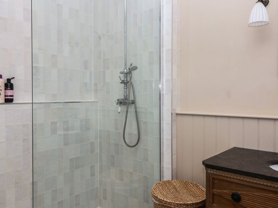 A shower with a glass partition and sink in a bathroom at The Old Vicarage in Merriott