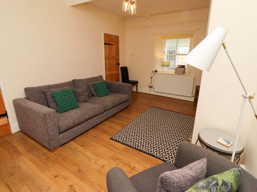 A living room with a sofa and lamp at Barleycorn Cottage in Belford