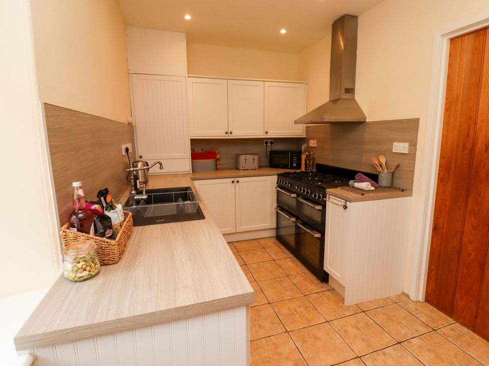 A kitchen with cabinets, stove and sink at Barleycorn Cottage in Belford
