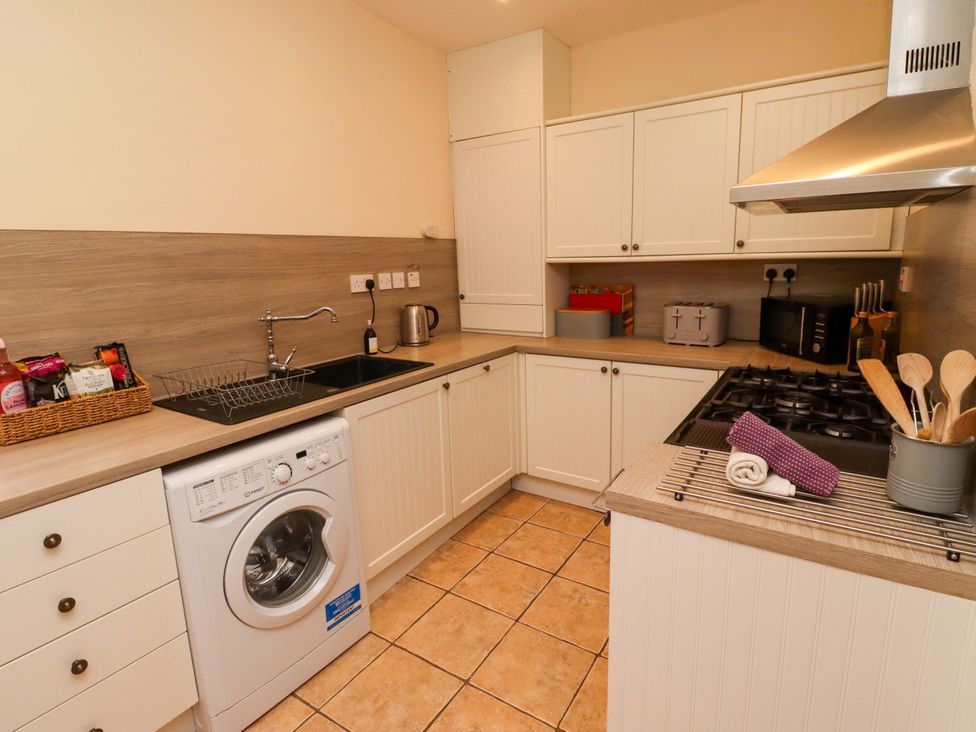 A kitchen with a washing machine and gas stove at Barleycorn Cottage in Belford