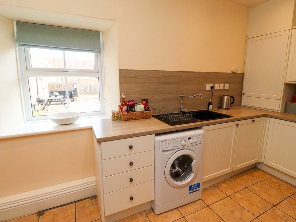 A kitchen with a washing machine and sink at Barleycorn Cottage in Belford