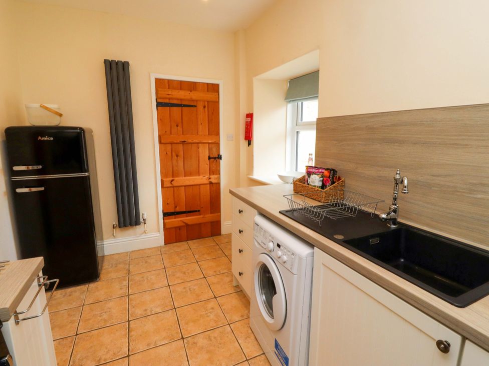 A utility room with a fridge and washing machine at Barleycorn Cottage in Belford