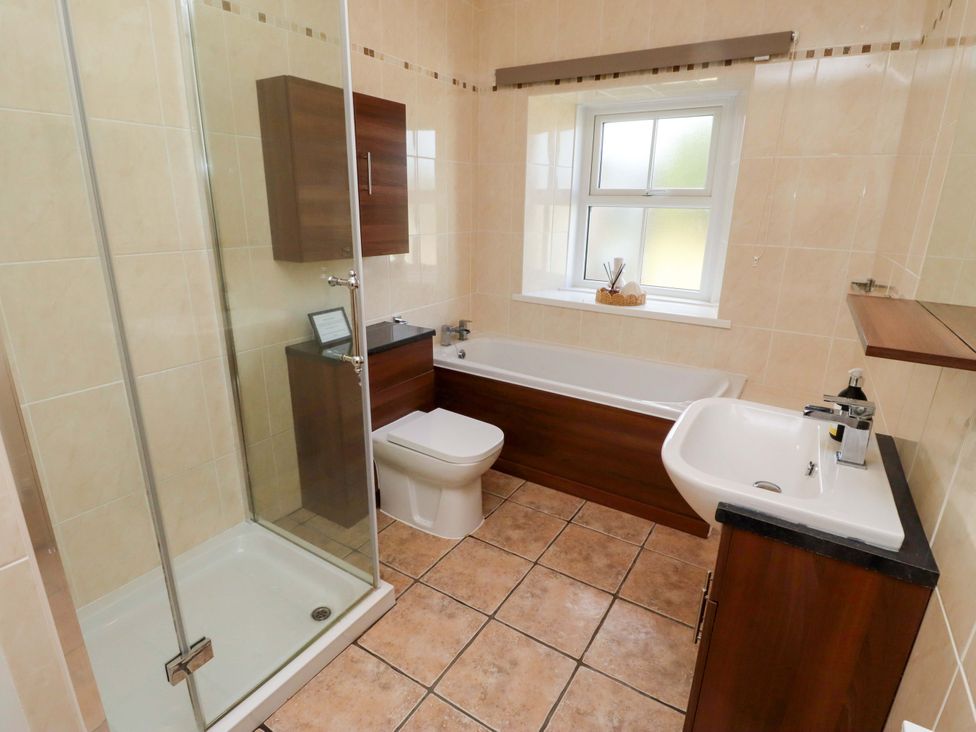 A bathroom with a shower, bathtub, toilet, and sink at Barleycorn Cottage in Belford