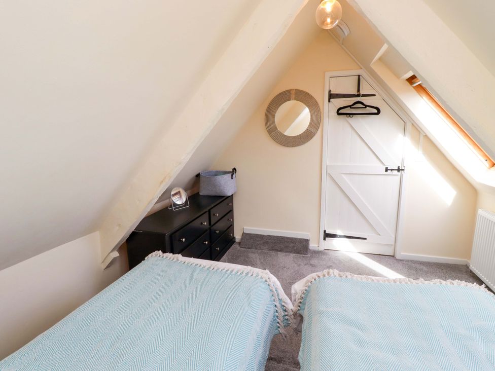 A bedroom with two beds and a dresser at Barleycorn Cottage in Belford