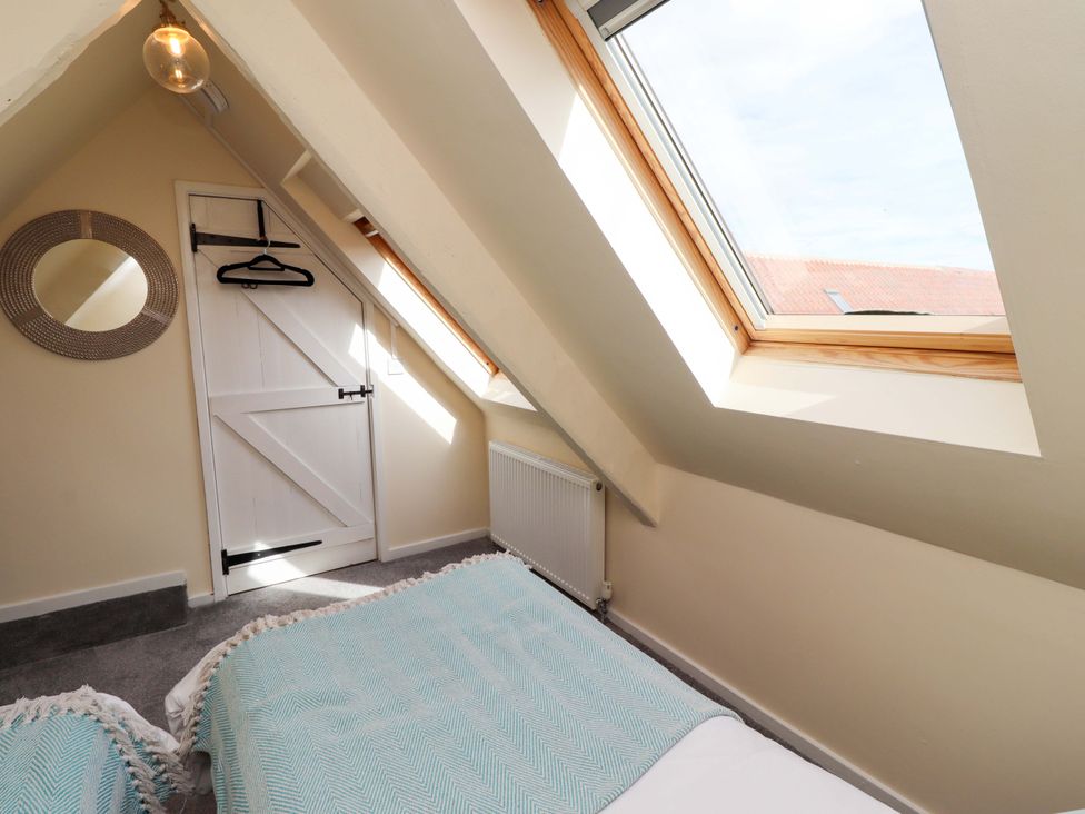 A bedroom with two beds and a door at Barleycorn Cottage in Belford