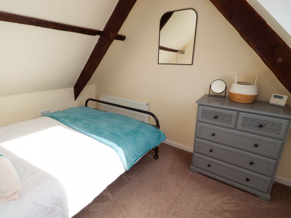 A bedroom with a bed, dresser, and mirror at Barleycorn Cottage in Belford