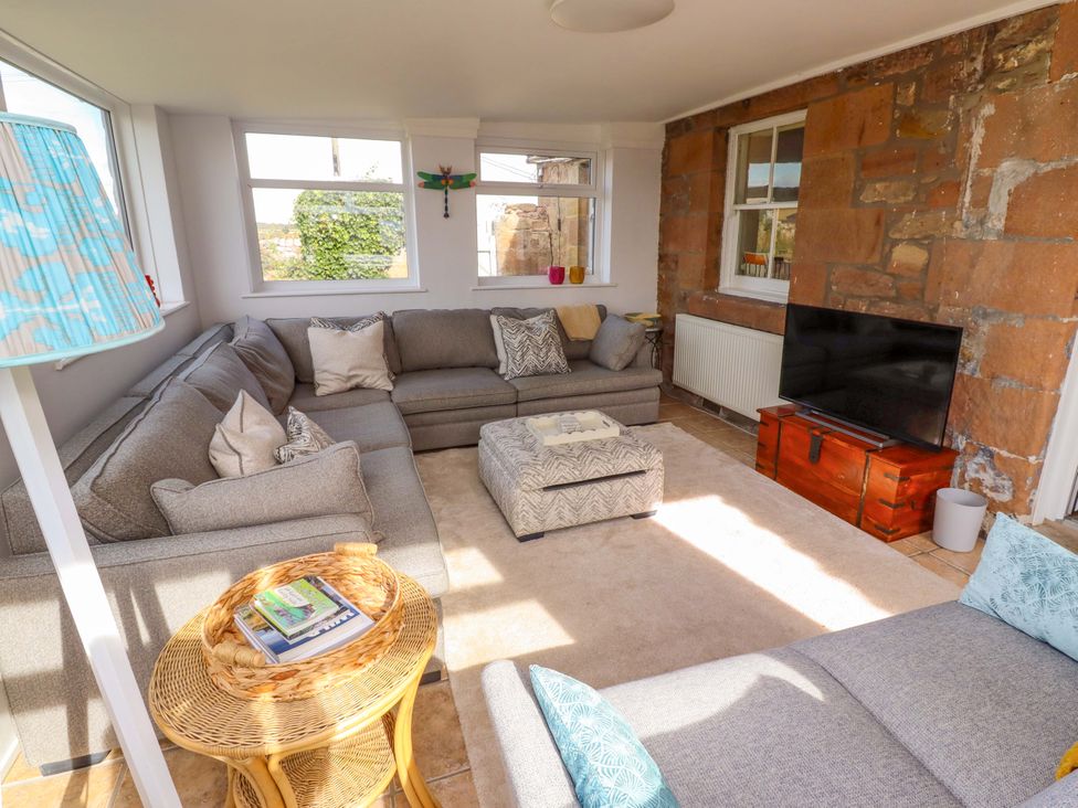 A living room with a sofa and television at Barleycorn Cottage in Belford