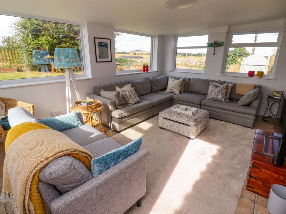 A living room with a sectional sofa and coffee table at Barleycorn Cottage in Belford