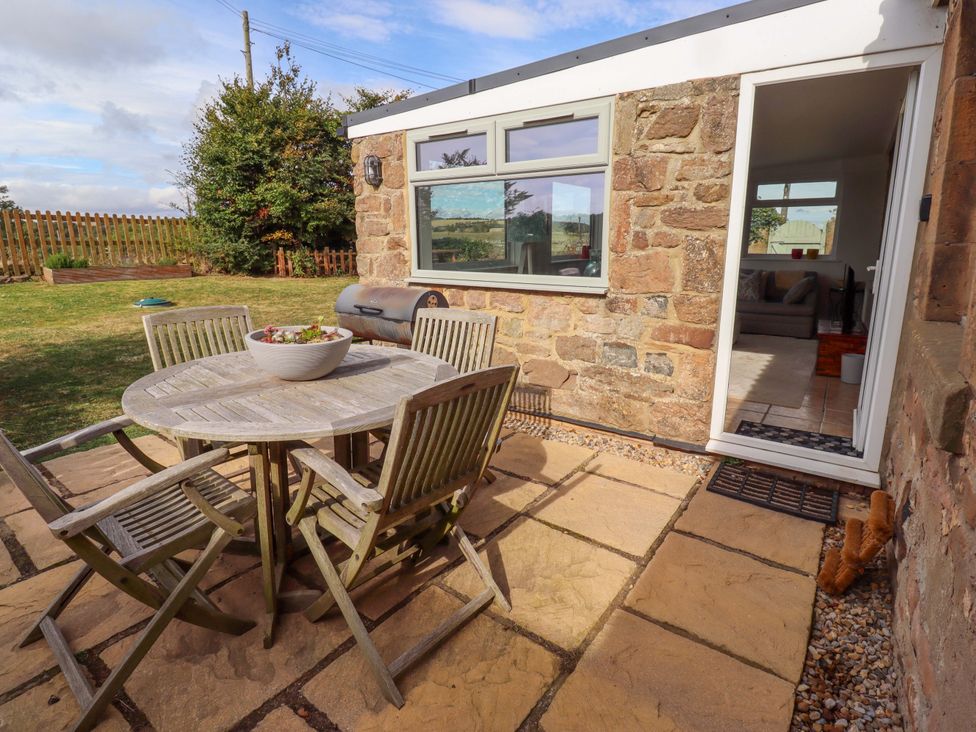 An outdoor patio area with a table and chairs at Barleycorn Cottage in Belford