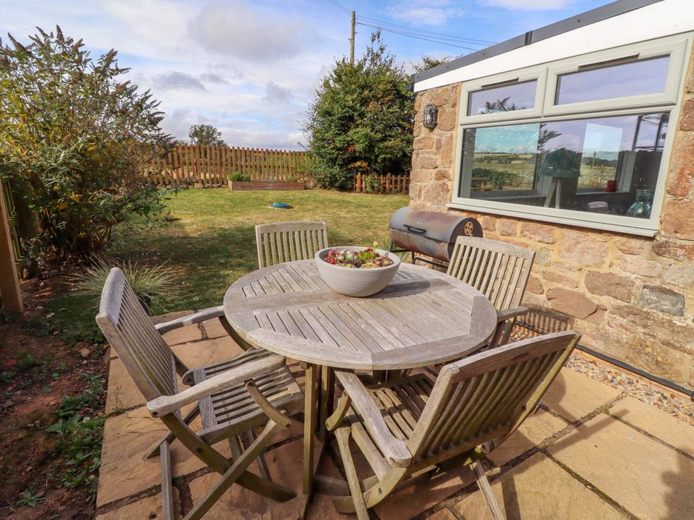 A garden with a wooden table and chairs at Barleycorn Cottage in Belford