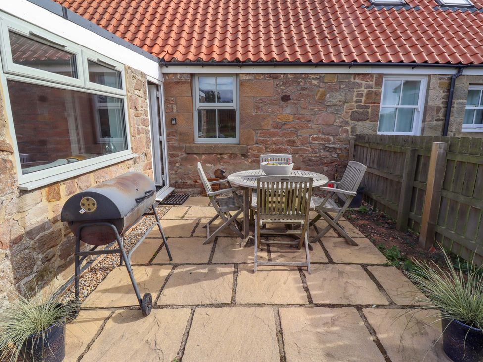 An outdoor area with a table, chairs, and a grill at Barleycorn Cottage in Belford