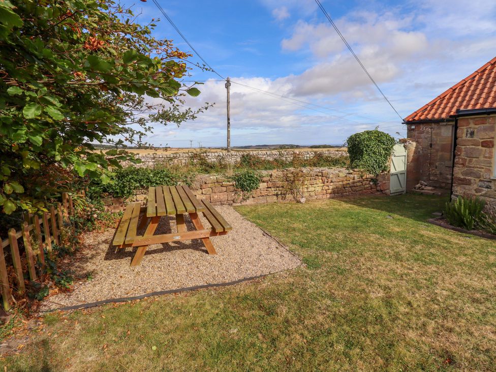 A garden with a picnic table and stone wall at Barleycorn Cottage in Belford