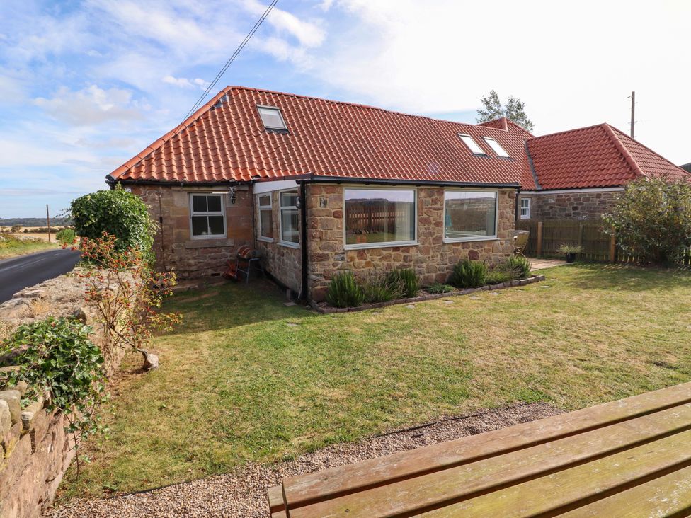 A cottage with a garden and windows at Barleycorn Cottage in Belford