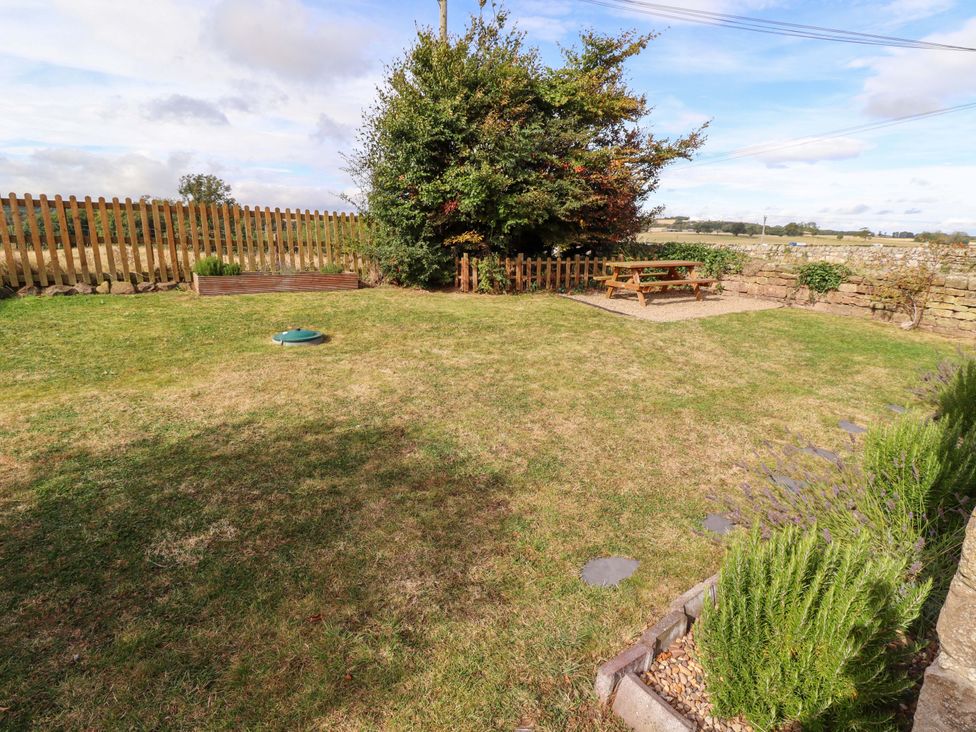 A garden with grass and seating area at Barleycorn Cottage in Belford