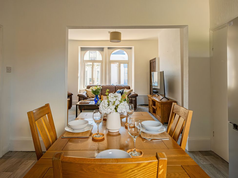 A dining room with a table and chairs looking into a living room at Flat 56 Newton Road Abertawe