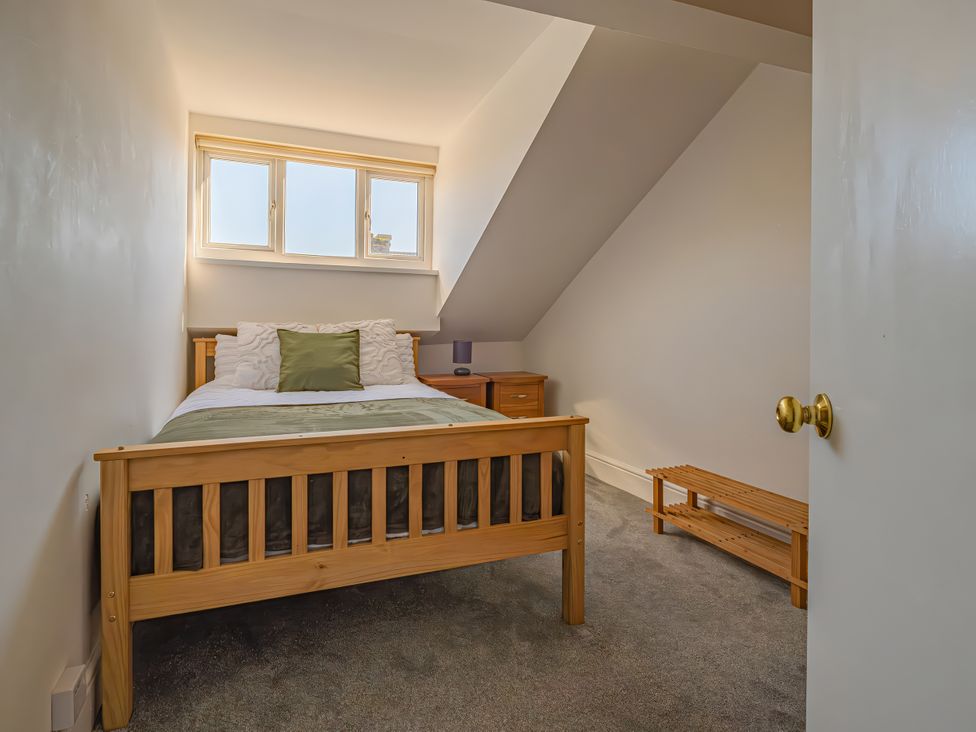 A bedroom with a wooden bed and nightstand at Flat 56 Newton Road Abertawe