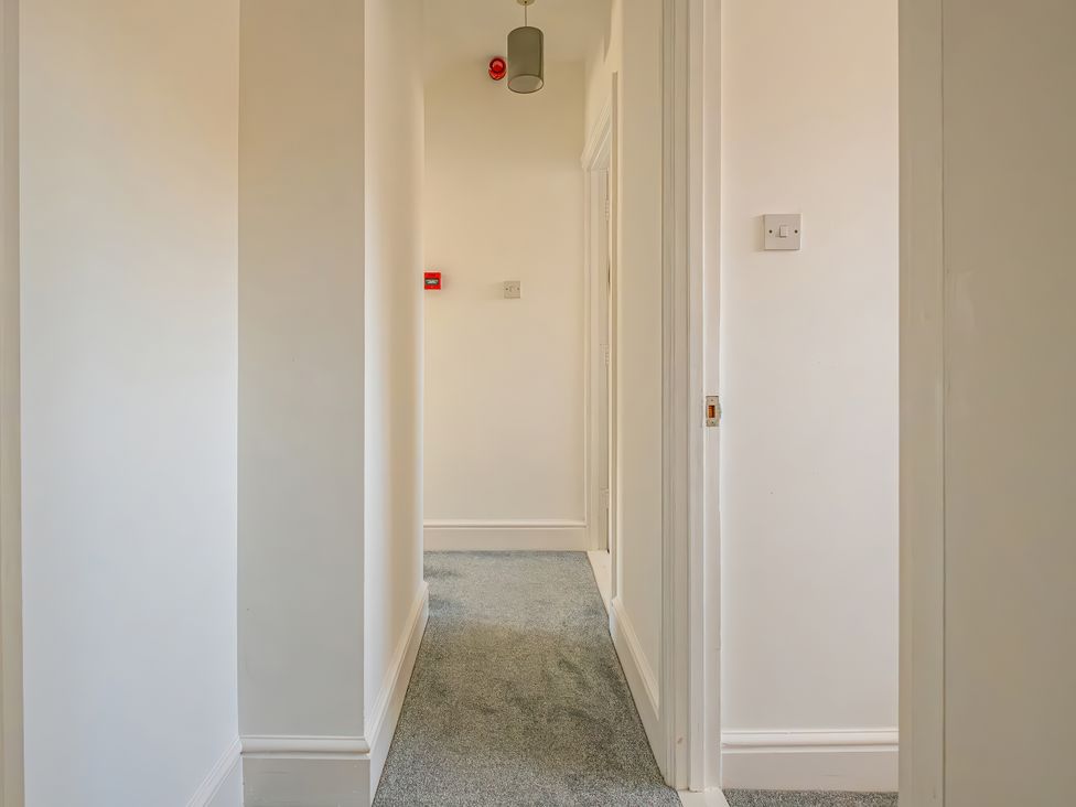 A hallway with carpet and a light fixture at Flat 56 Newton Road Abertawe