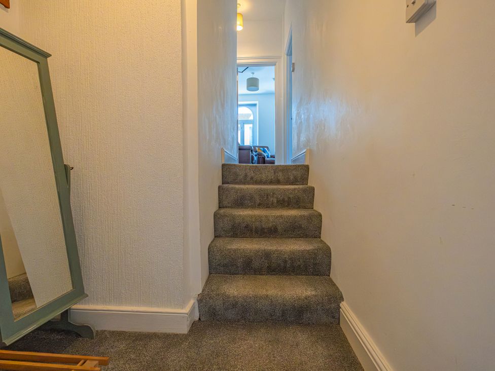 A hallway with stairs and a mirror at Flat 56 Newton Road in Abertawe