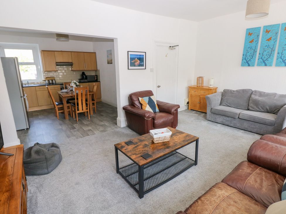 A living room with a sofa and coffee table and a dining area at Flat 56 Newton Road in Mumbles