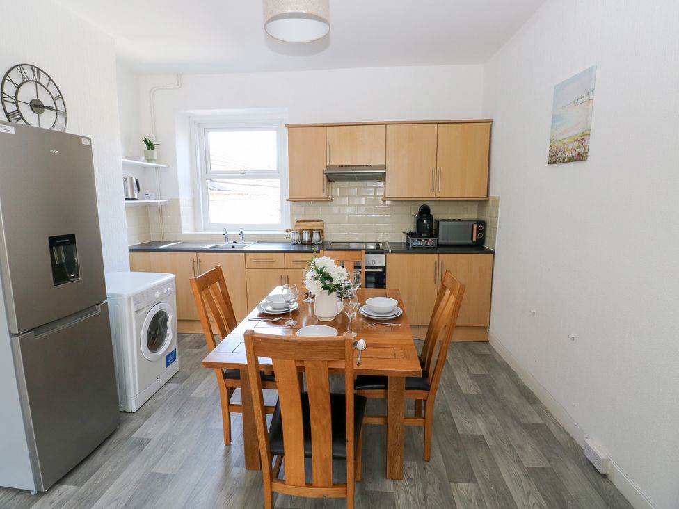 A kitchen with appliances and a dining table at Flat 56 Newton Road Mumbles