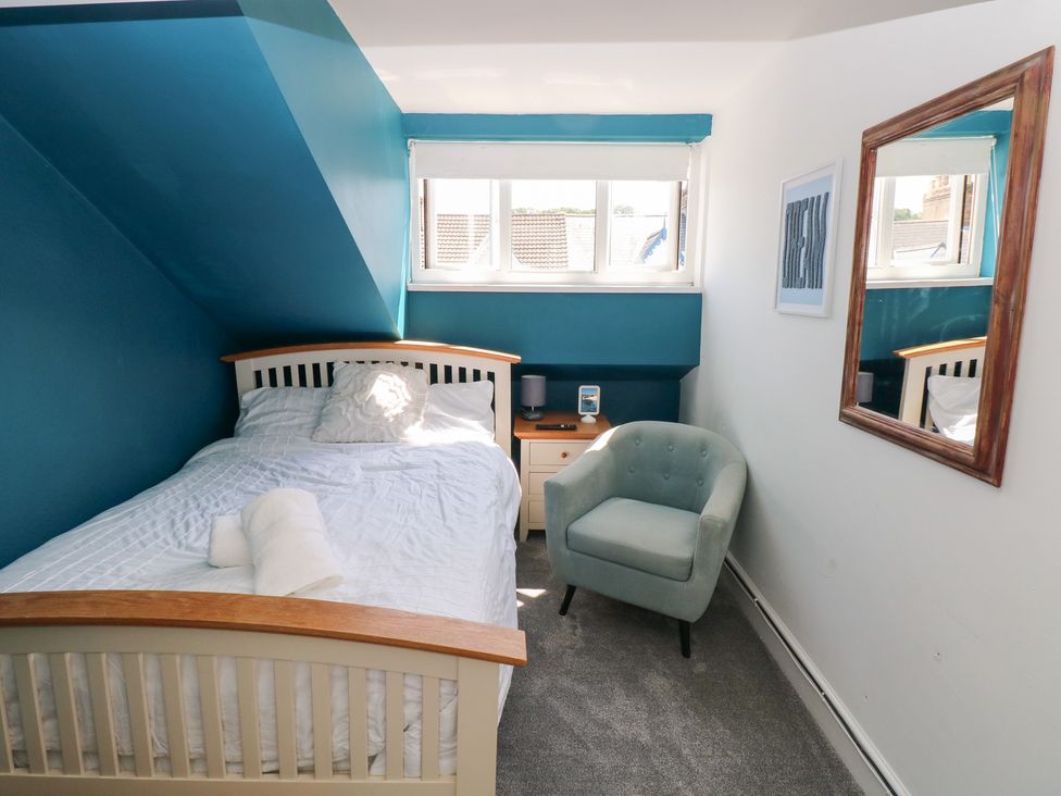 A bedroom with a bed and armchair at Flat 56 Newton Road in Mumbles