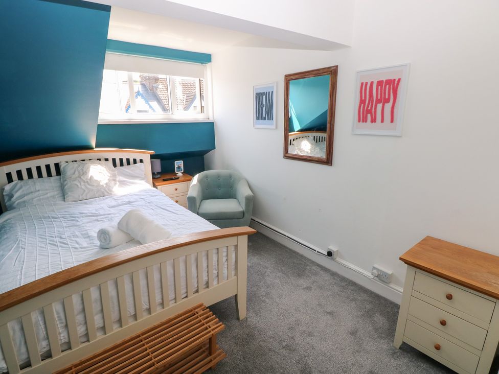 A bedroom with a bed and armchair at Flat 56 Newton Road Mumbles
