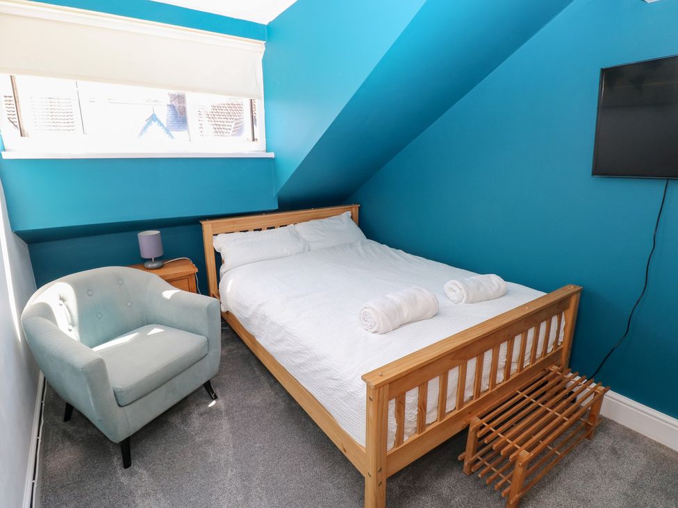 A bedroom with a bed and chair at Flat 56 Newton Road in Mumbles