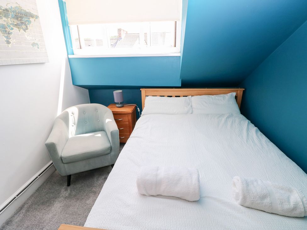 A bedroom with a bed and armchair at Flat 56 Newton Road in Mumbles