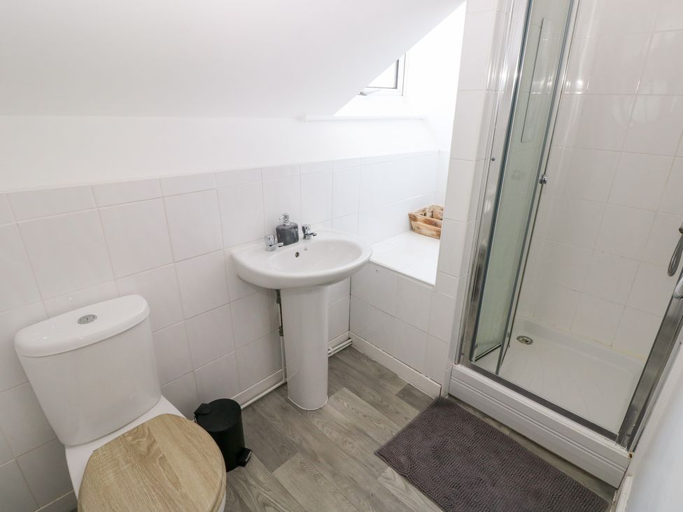 A bathroom with a toilet, sink, and shower at Flat 56 Newton Road in Mumbles