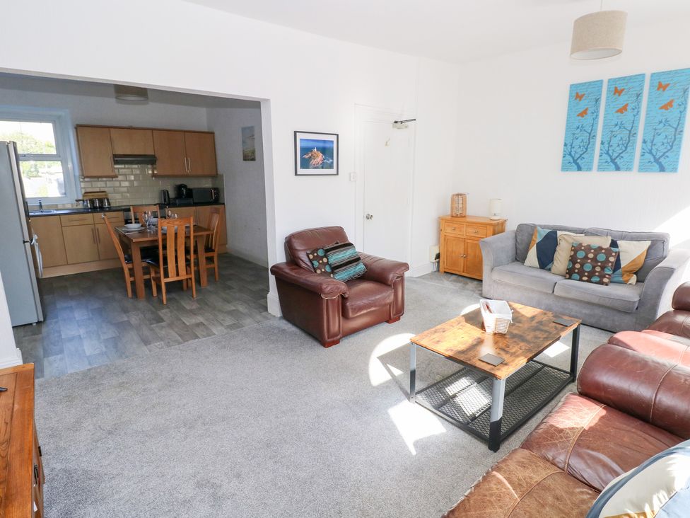 A living room with a sofa and dining area at Castleview Coastal Comfort Mumbles