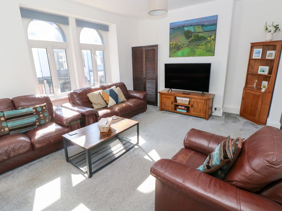 A living room with sofas, a coffee table, and a television at Castleview Coastal Comfort in Mumbles
