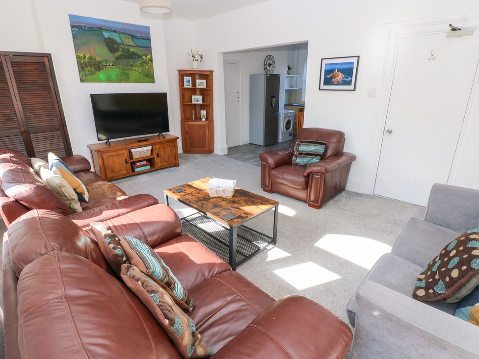 A living room with a sofa and television at Castleview Coastal Comfort Mumbles