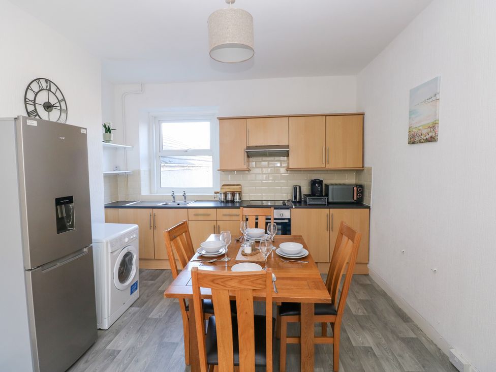 A kitchen with a dining table and appliances at Castleview Coastal Comfort in Mumbles