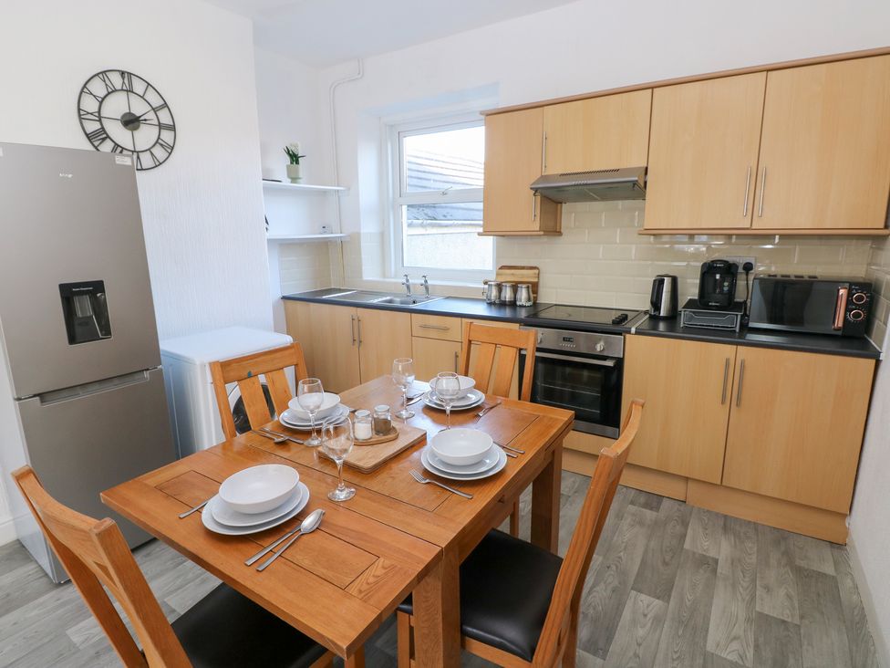 A kitchen with a dining table and appliances at Castleview Coastal Comfort in Mumbles