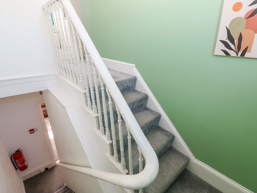 A staircase with a handrail and painting at Castleview Coastal Comfort in Mumbles