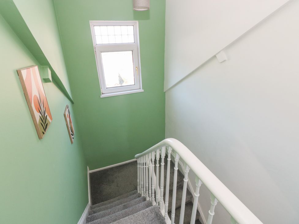 A staircase with green walls and a window at Castleview Coastal Comfort, Mumbles