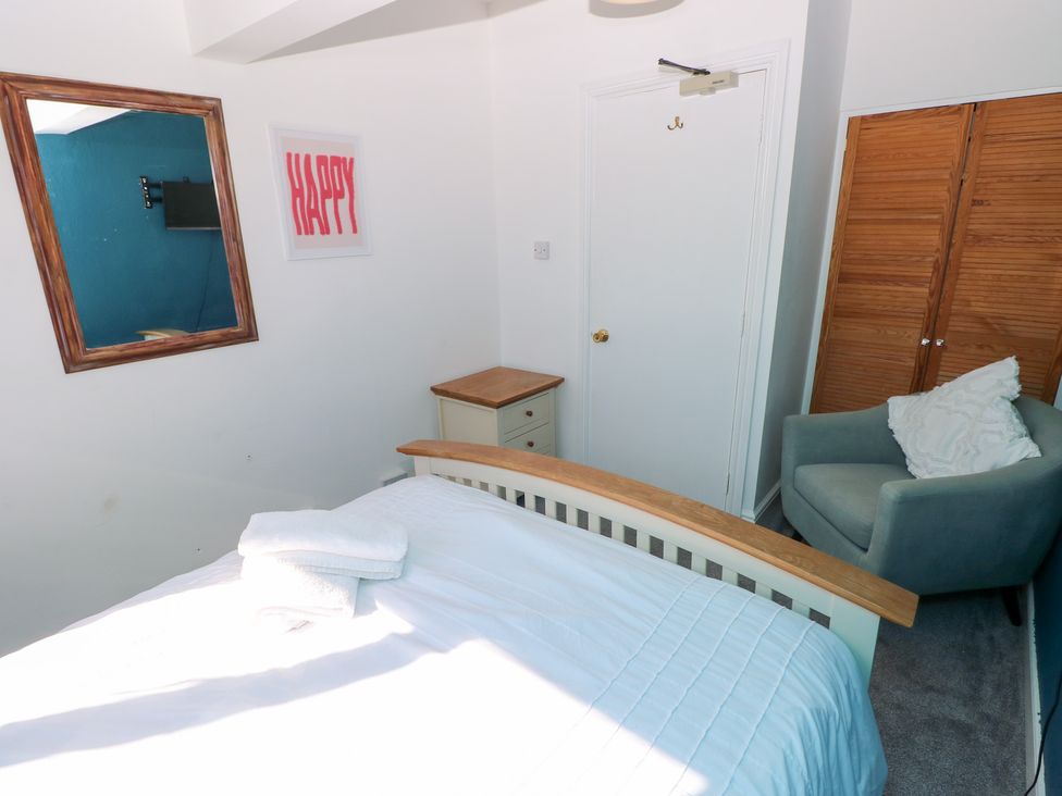 A bedroom with a bed, chair, and wardrobe at Castleview Coastal Comfort in Mumbles
