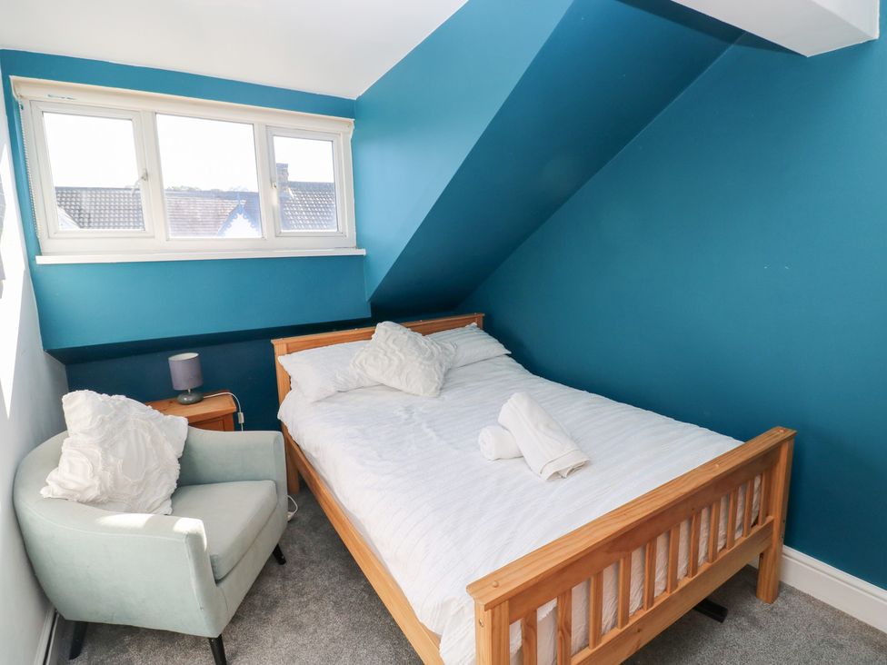 A bedroom with a bed and chair at Castleview Coastal Comfort in Mumbles