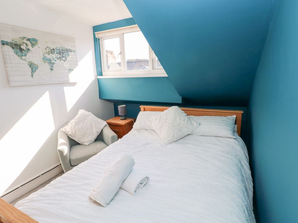 A bedroom with a bed, nightstand, and map at Castleview Coastal Comfort in Mumbles