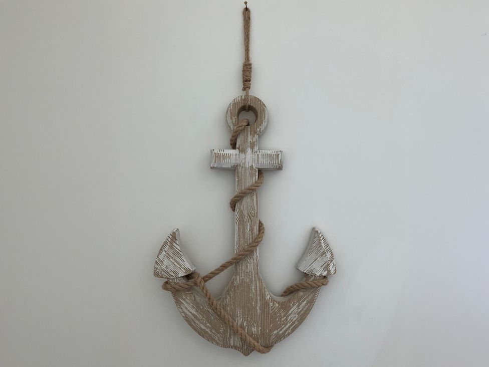 A decorative wooden anchor with rope hanging on a wall at Claire Cottage 