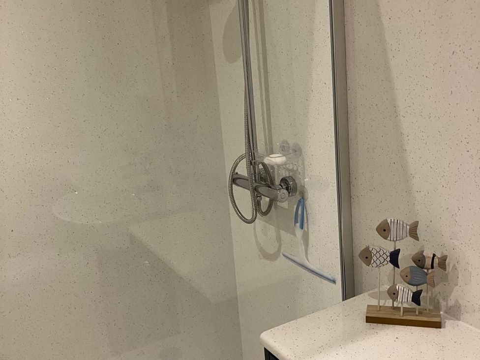 A bathroom with a shower and a fish decoration at Claire Cottage