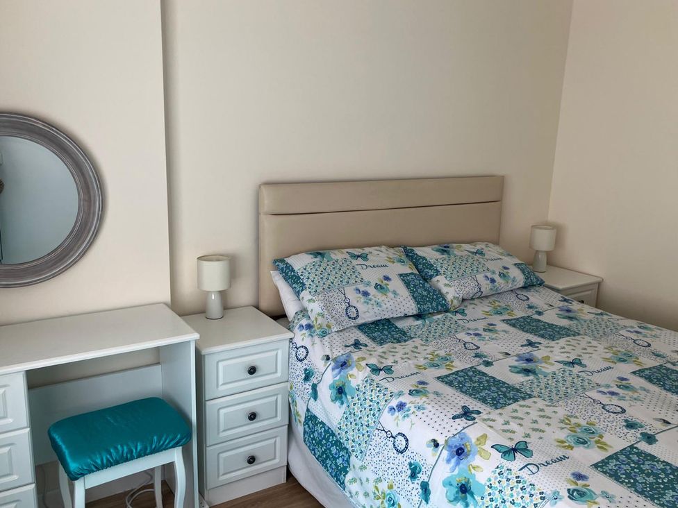 A bedroom with a bed, desk, mirror and nightstand at Claire Cottage