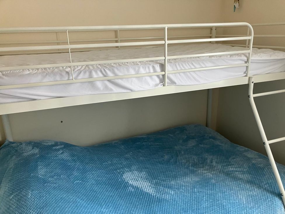 A bunk bed with a top mattress and a blue bottom mattress at Claire Cottage
