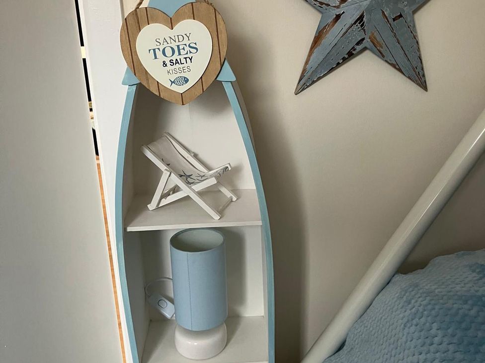 A shelf with a sign, chair model, and lamp at Claire Cottage