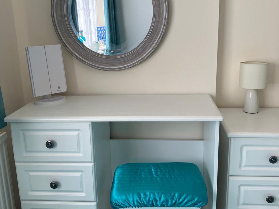 A desk with a mirror and lamp in a bedroom at Claire Cottage